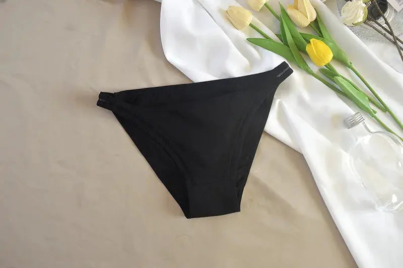 Women’s black bikini briefs, solid-color underwear on beige background