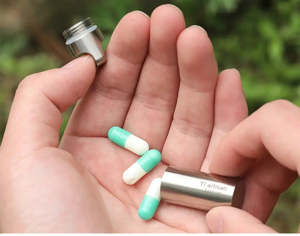 Tiartisan titanium mini EDC pill bottle with sealed cap; portable pill container showing green and white capsules
