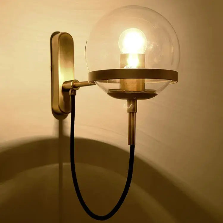 Modern glass ball wall lamp with brass finish, clear globe, wall-mounted fixture