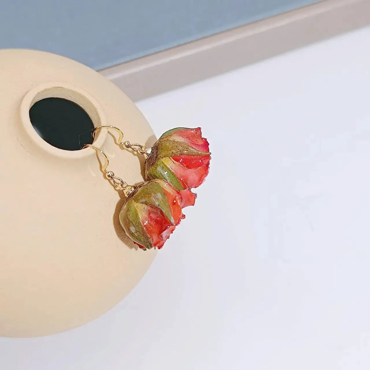 Red rose epoxy resin drop earrings with real rose buds on a gold-tone chain.