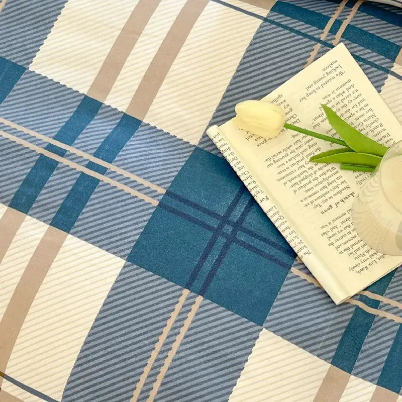 Blue plaid bedding set with beige stripes, shown with a book and tulip.
