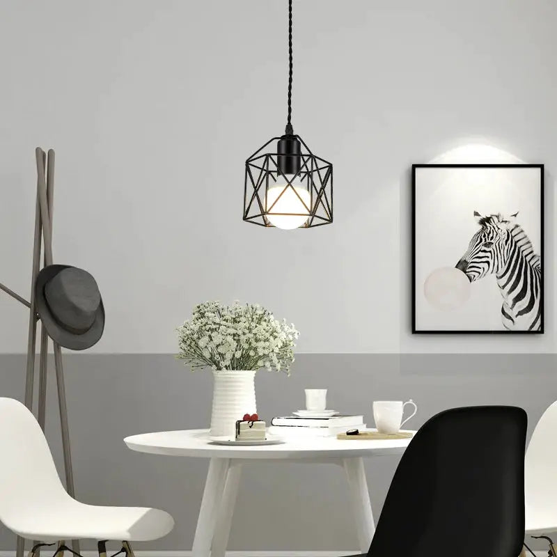 Modern LED pendant light with black iron cage and gold finish, hanging over a white round dining table.
