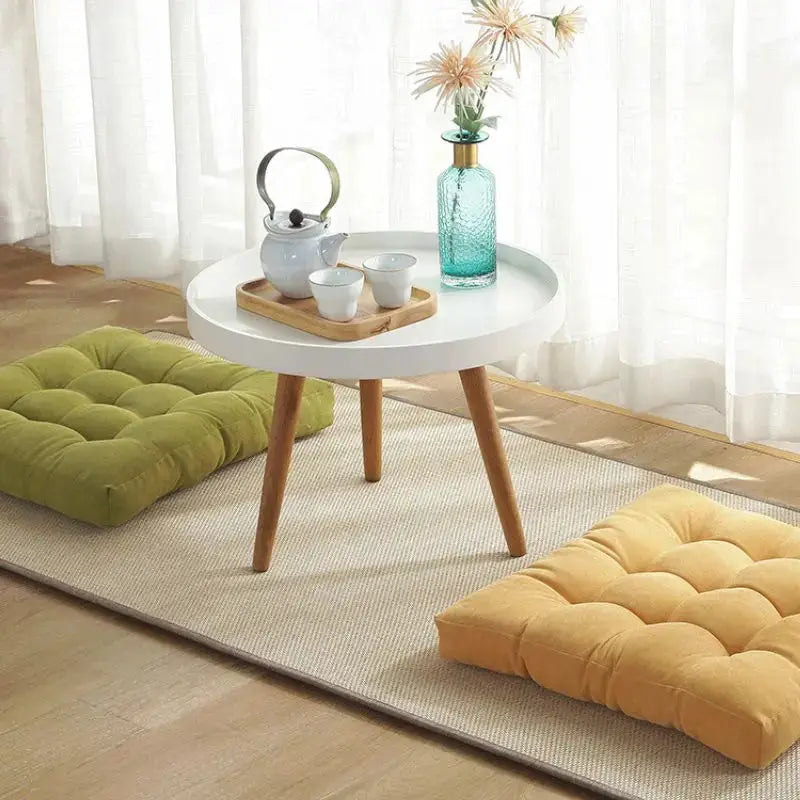 Floor pillows; two tufted square cushions in olive green and mustard yellow for floor seating.
