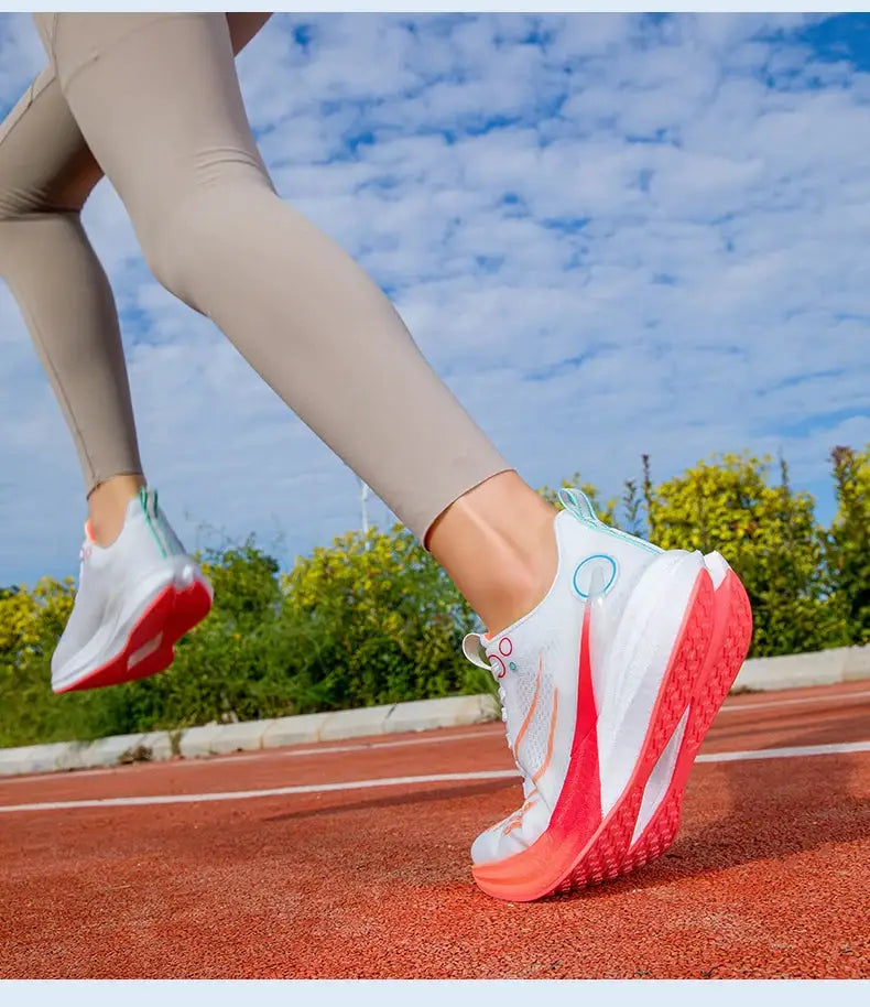 Pair of marathon running shoes on track, white with orange outsole and teal accents