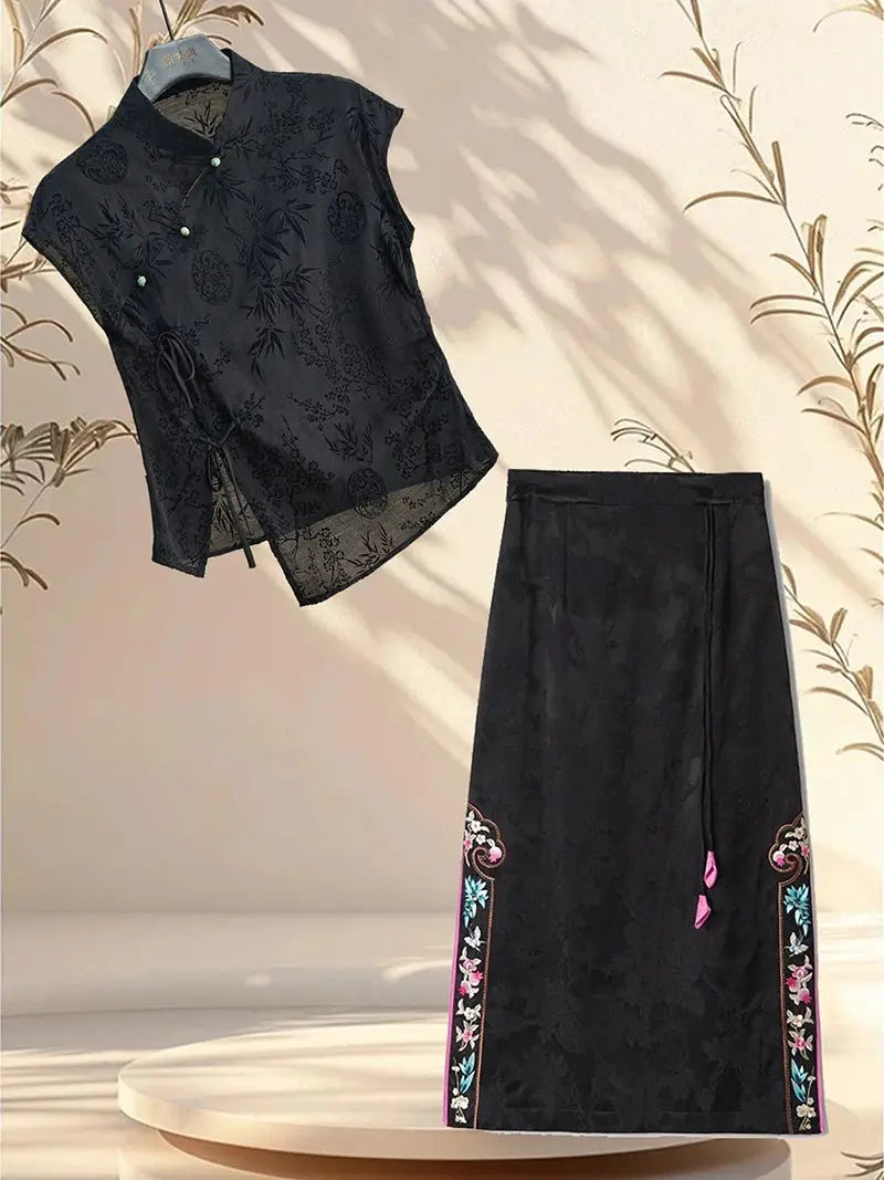 Two-piece black jacquard cheongsam-style top with mandarin collar and side tie, paired with a black embroidered long skirt.