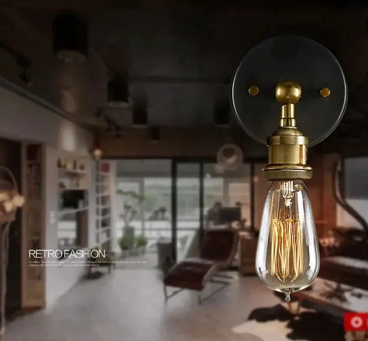 American single-head wall lamp, brass industrial fixture with Edison bulb and black round backplate.