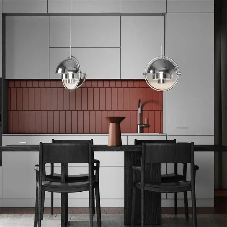 Pair of pendant lights over kitchen island; chrome-iron spherical fixtures with circular frame.