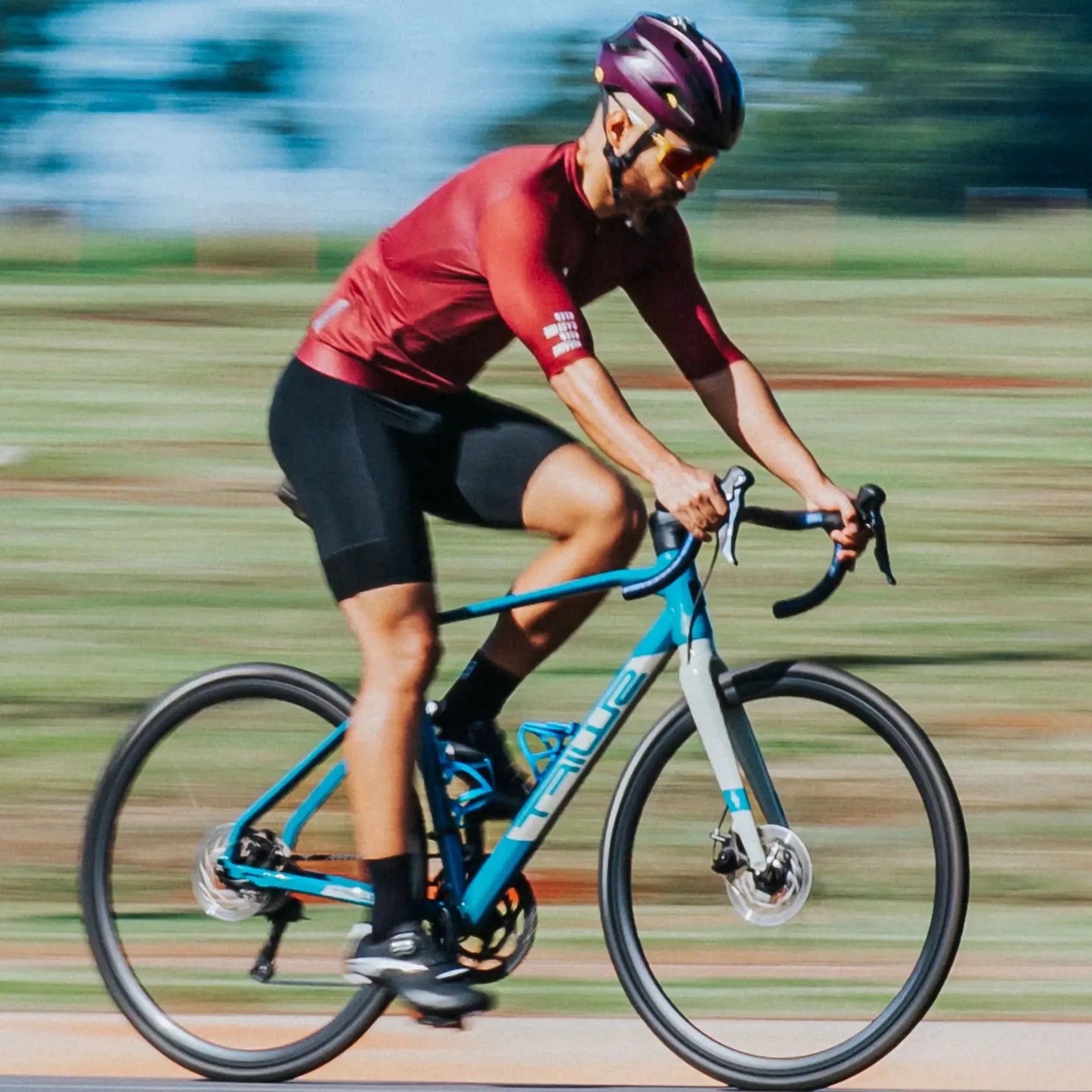DAREVIE women's cycling jersey, red SPF 50+ breathable shirt worn by cyclist on blue road bike