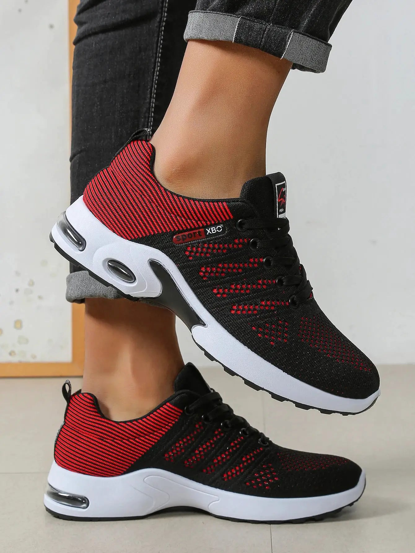 Men's running shoes, black and red knit with lace-up, breathable upper and cushioned non-slip sole; two shoes shown