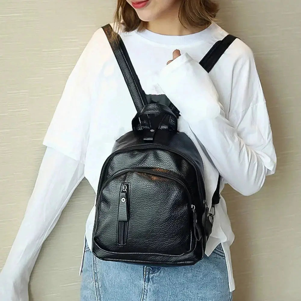 Mini black faux-leather men's backpack with front zip pocket and compact shoulder design.