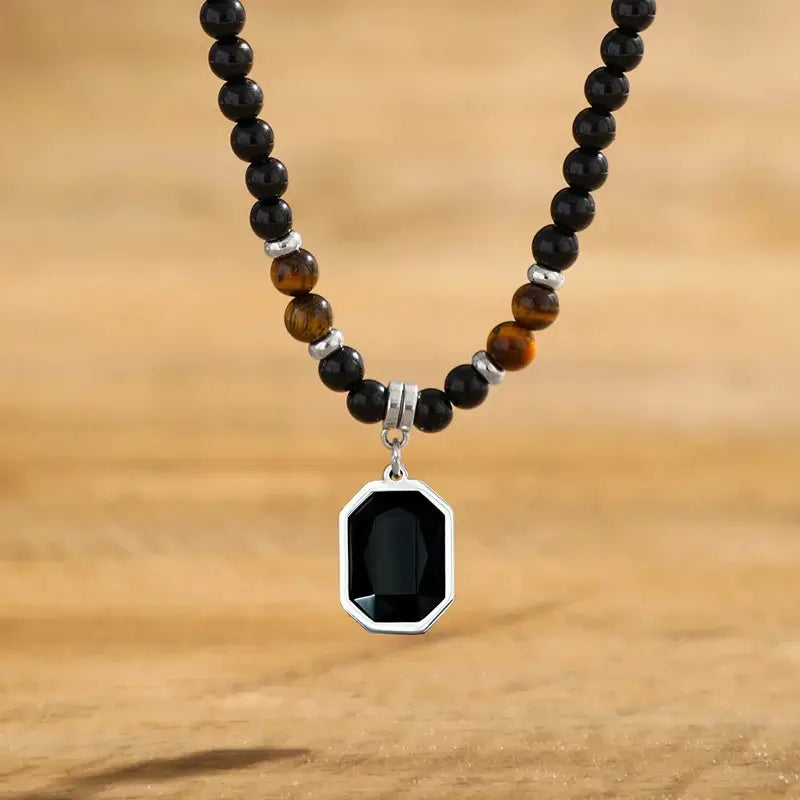Beaded clavicle necklace with black and tiger eye beads and octagonal black stone pendant in silver bezel