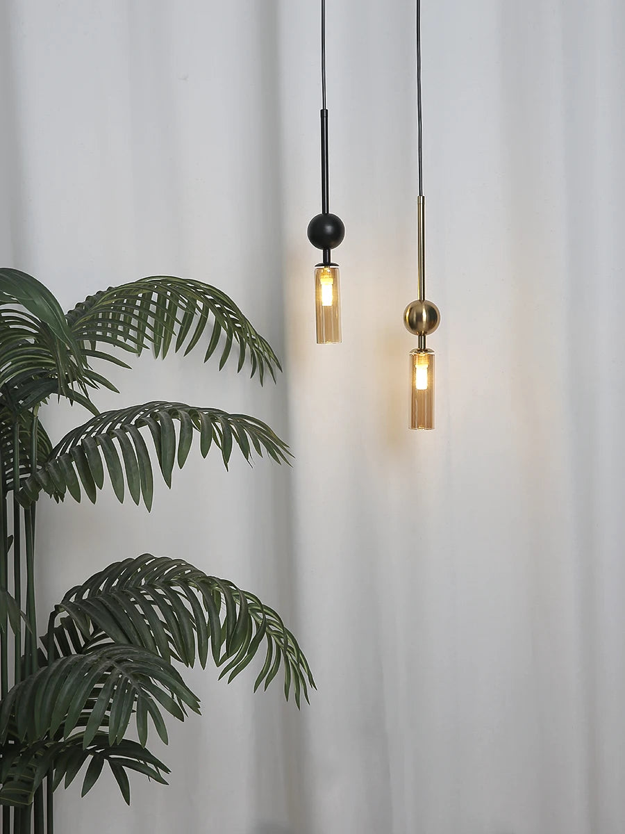 Two Nordic Light pendant lights by Simples Market in gold and black iron with glass cylinder shades
