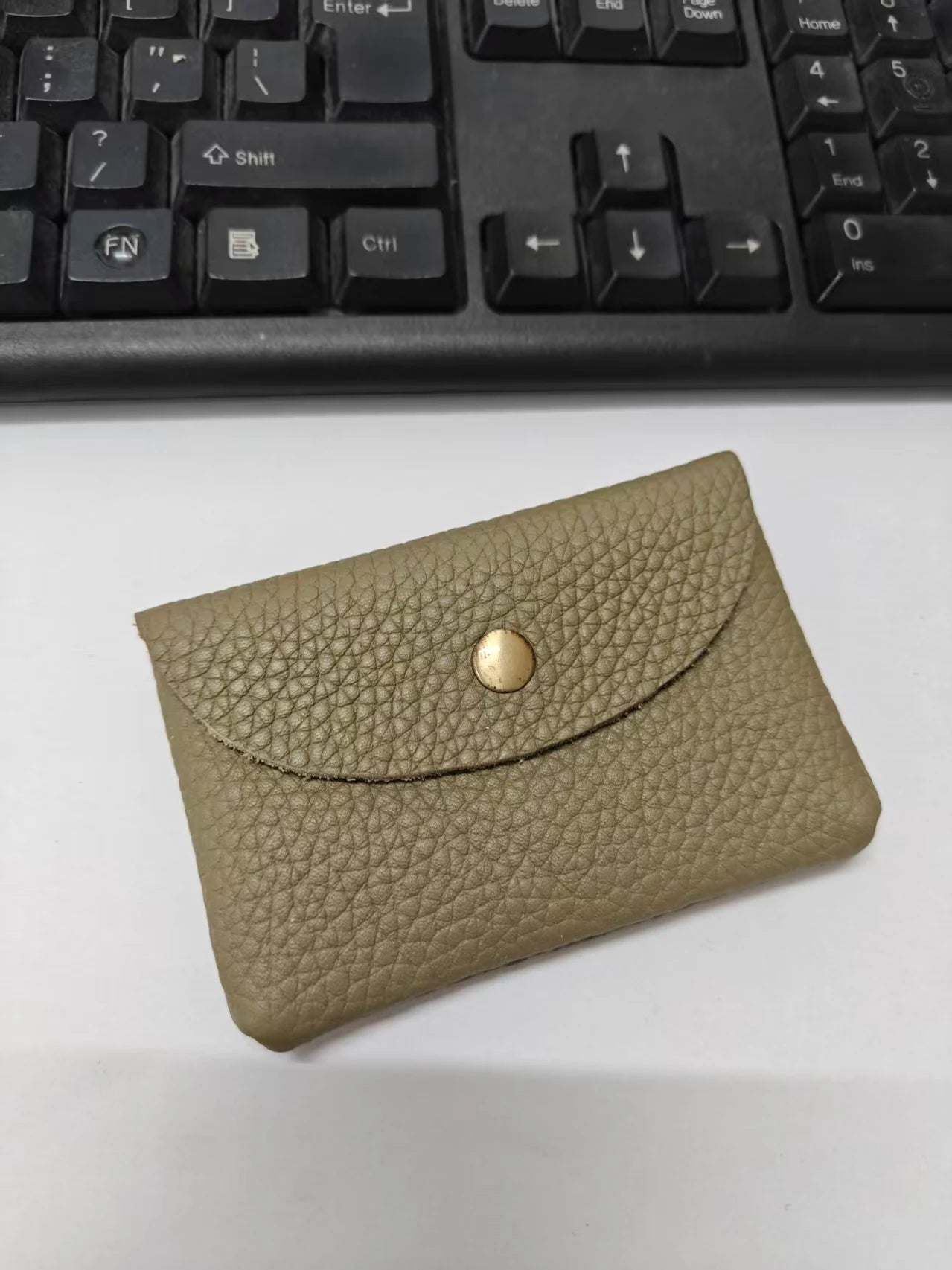 Tan pebble-grain leather card holder with envelope-style flap and gold-tone snap.