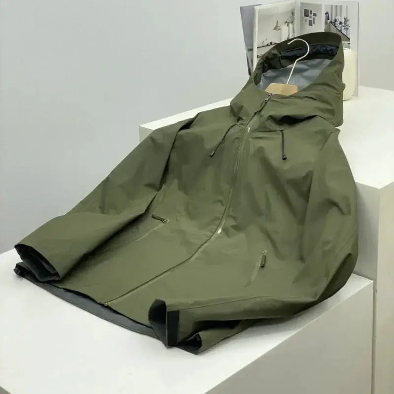 Men's olive green outdoor windproof soft shell jacket with hood and zip pockets.