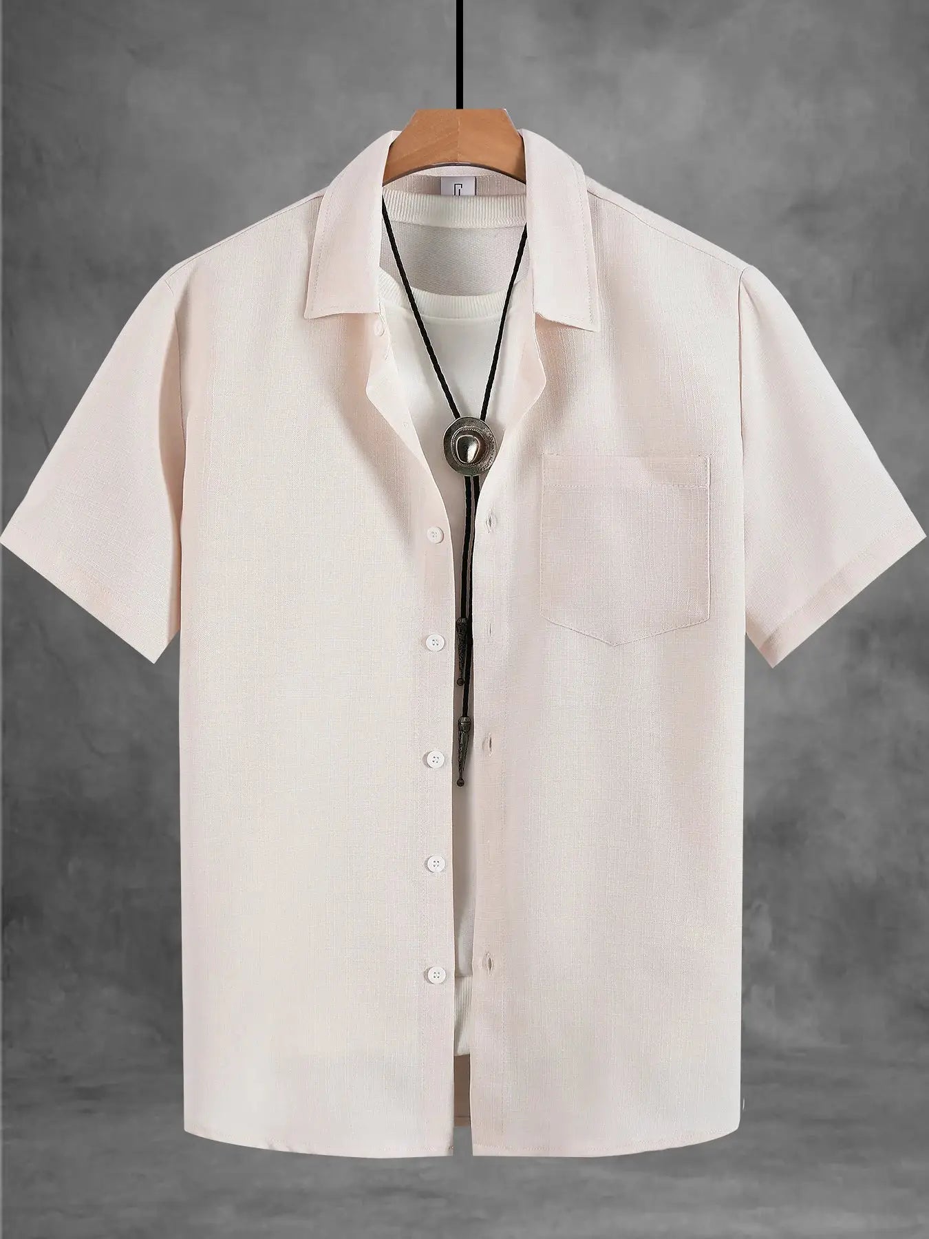 Men's cream linen short-sleeve shirt and black cord necklace by Simples Market, displayed on hanger; chest pocket.