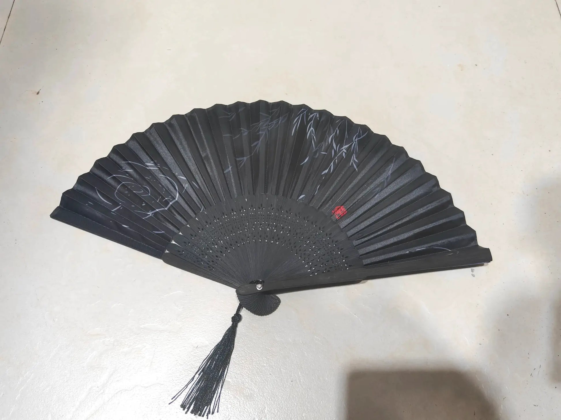 Black bamboo hand folding fan with tassels and gray leaf design