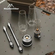 Mountainhiker outdoor gas light set components with glass chimneys and brass burner on a metal table.