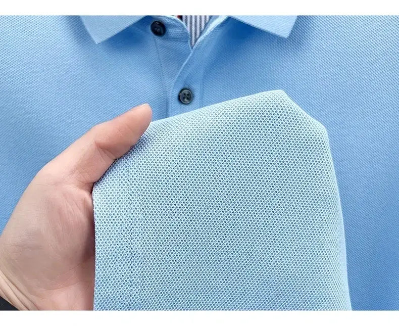 Light blue men's polo shirt with textured pique fabric; close-up of a hand holding the short sleeve.