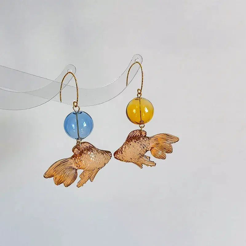 Pair of goldfish pendant drop earrings with copper-toned koi charms and blue and yellow beads by Simples Market
