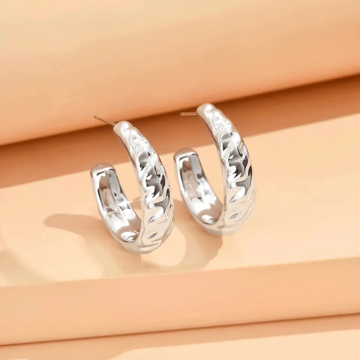 Silver hoop earrings with geometric irregular shape and hammered texture, pair