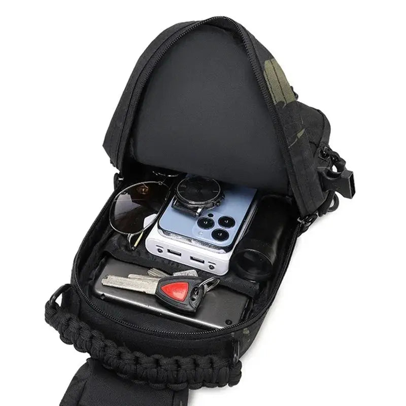 Simples Market black tactical chest bag with MOLLE sling, opened to reveal sunglasses, phone, keys and watch