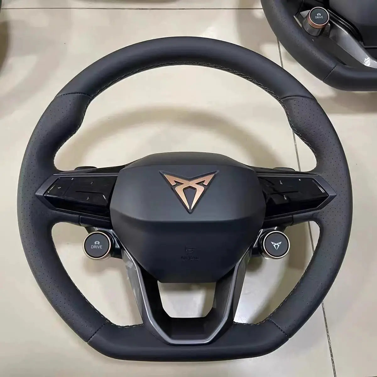 Steering wheel with perforated black leather grip and copper center emblem