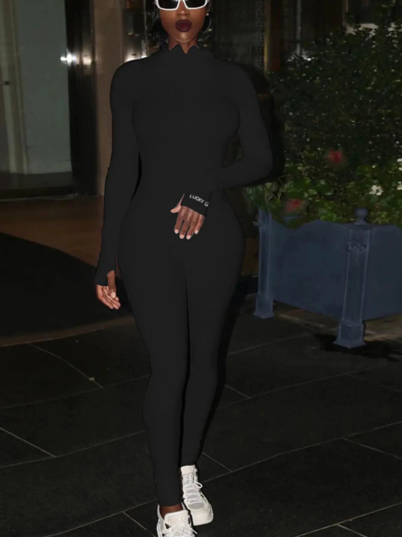 Black knitted jumpsuit by Simples Market; long sleeves, ruffled high-neck, bodycon fit