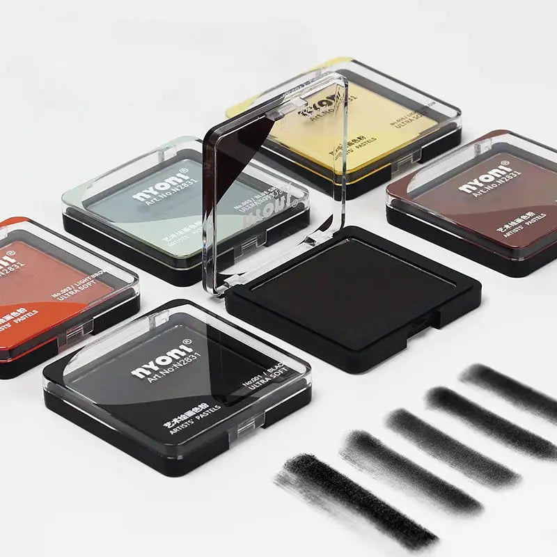 Nyom artist pastel and charcoal drawing set by Simples Market; assorted color pans in clear cases with a black block