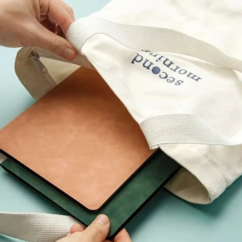 A5 reusable whiteboard notebook with tan cover and green underside, tucked into a light canvas tote