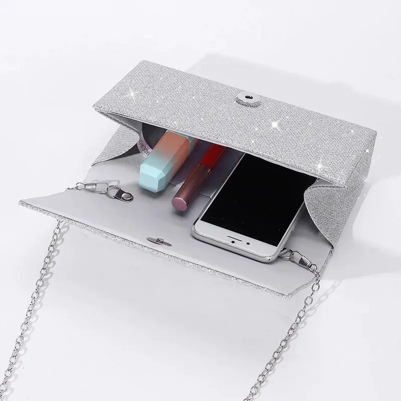 Simples Market glittery silver evening clutch with chain strap, open to reveal phone and makeup items