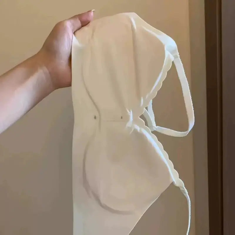 White sports bra held by hand, side view showing a thin back strap