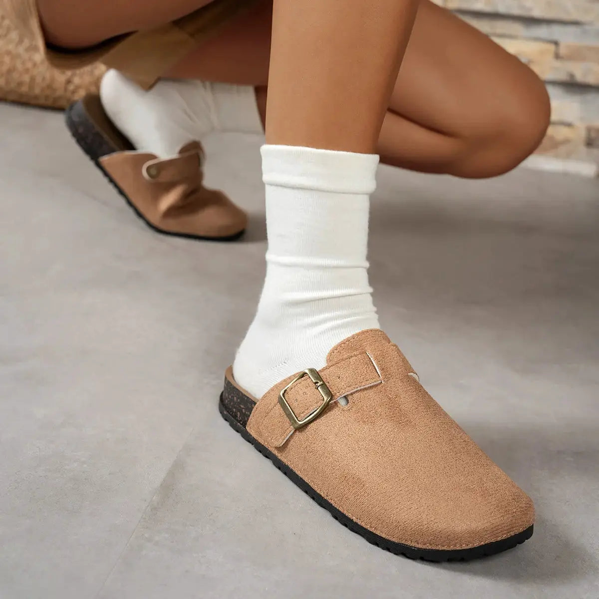 Pair of tan suede buckle loafers for women; flat casual shoes with gold-toned buckle and black sole.