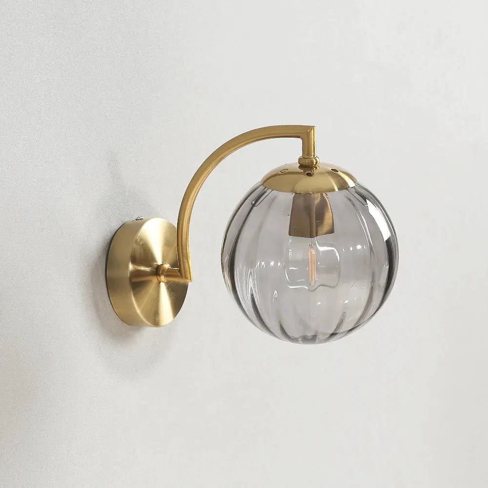 Modern LED wall lamp with brass curved arm and clear glass globe shade