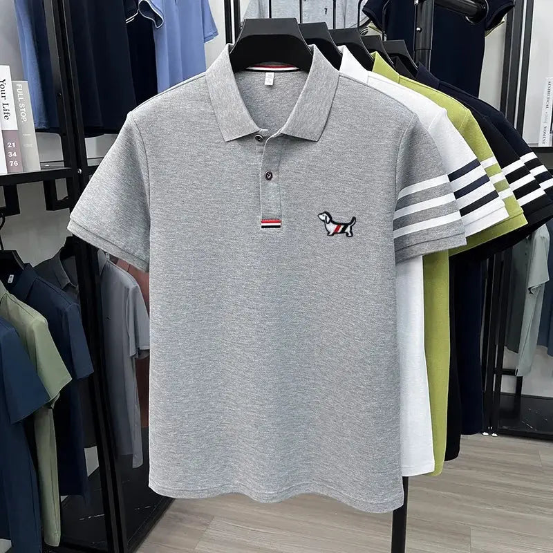 Grey polo shirt with short sleeves and collar; chest puppy embroidery and striped sleeve detail.