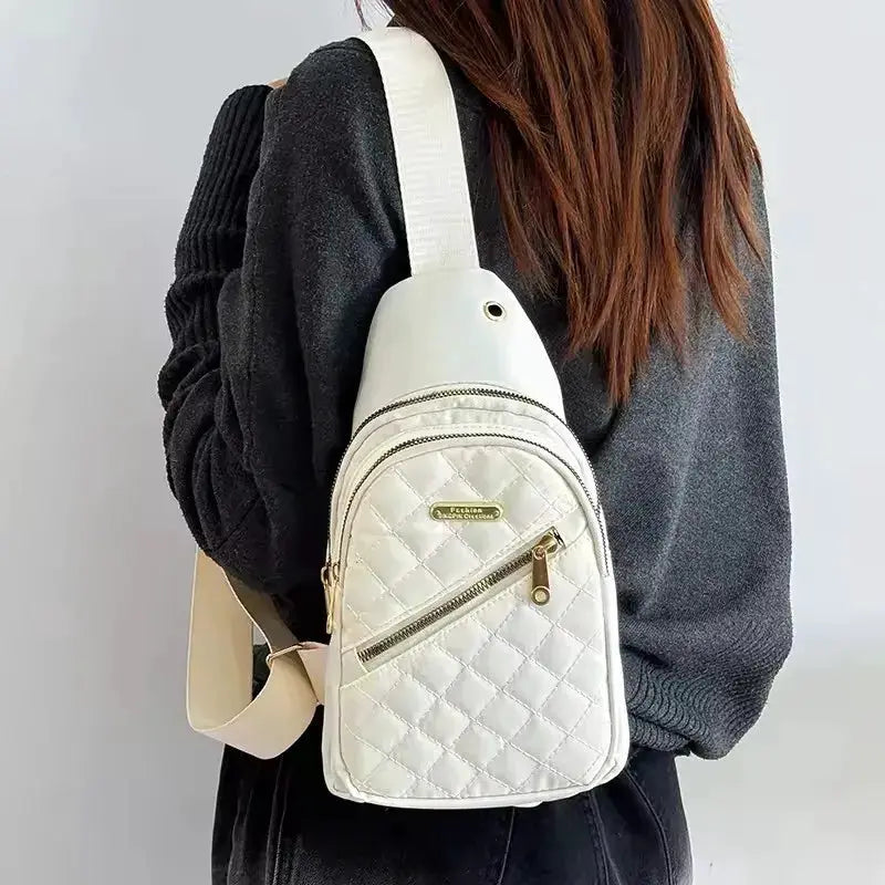 Backpack white quilted fabric with gold zippers and front zip pocket, Simples Market logo visible, worn as crossbody.
