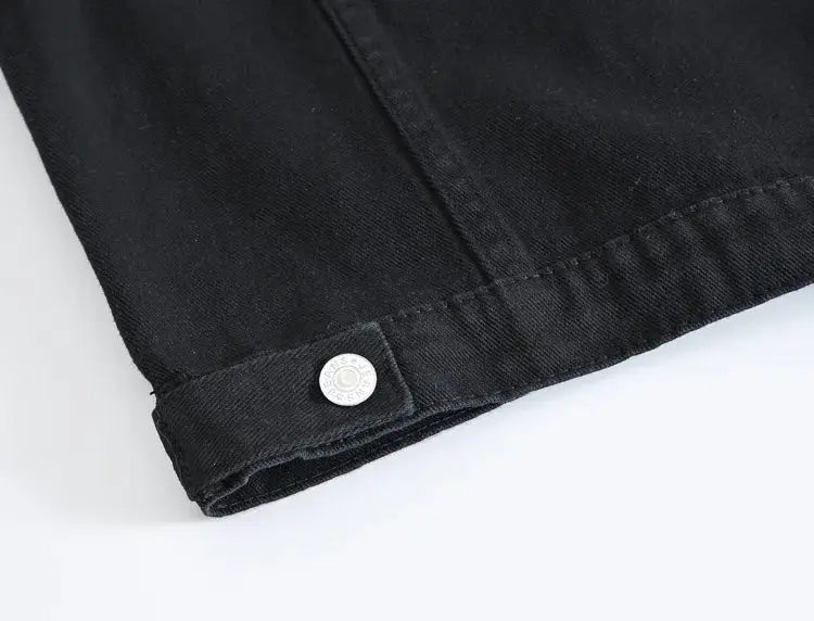 Black denim jacket sleeve cuff with metal snap button close-up