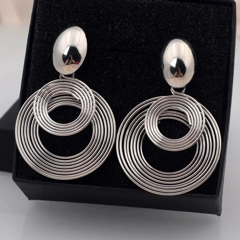 Pair of large silver-tone circular hoop earrings with concentric rings, dangle style