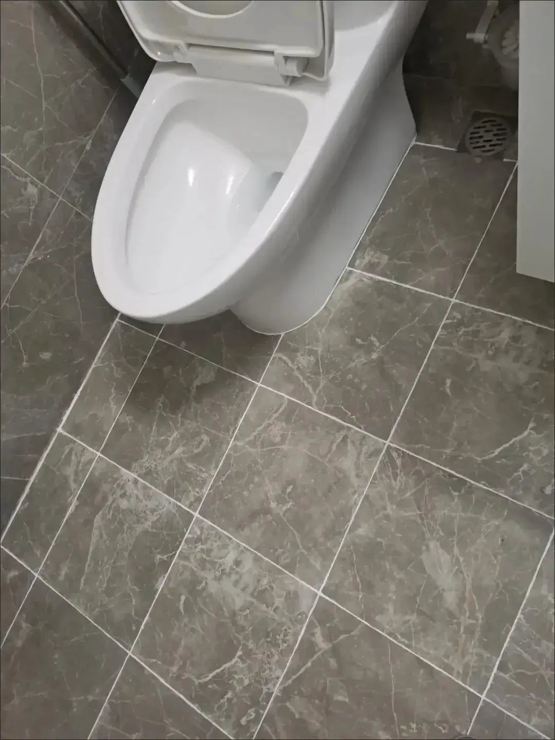 Waterproof tile grout marker pen for bathroom floors and walls; gray marble tile with a toilet and visible grout lines.