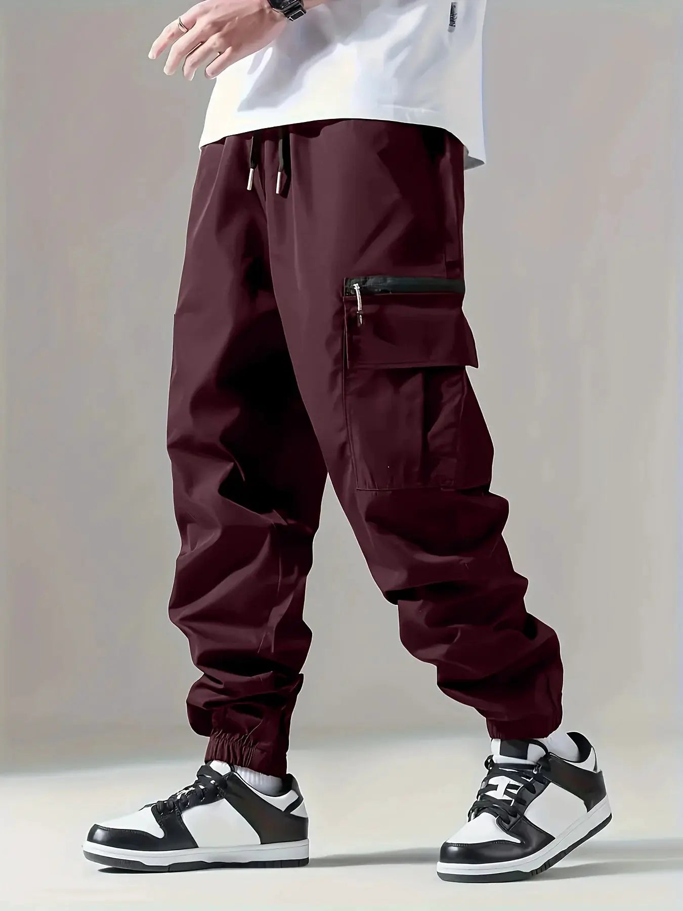 Men's burgundy cargo pants with multiple pockets, including zippered thigh pocket and drawstring waist