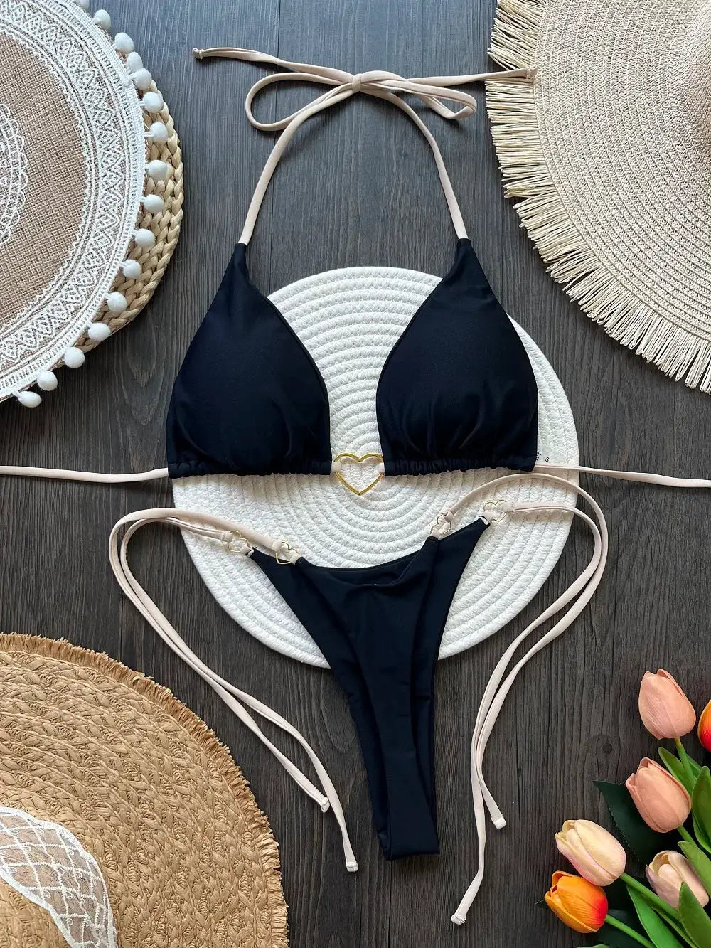 Two-piece black halter bikini with triangle cups, beige string ties, and gold heart ring detail