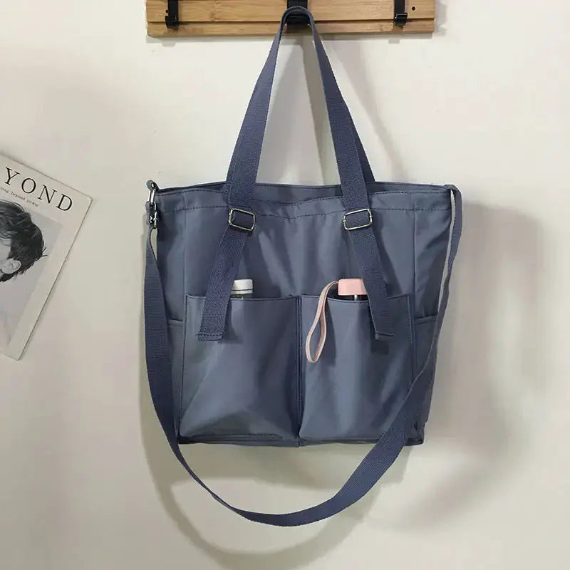 Simples Market waterproof Oxford large-capacity women’s handbag with dual handles and crossbody strap, blue-gray pockets.