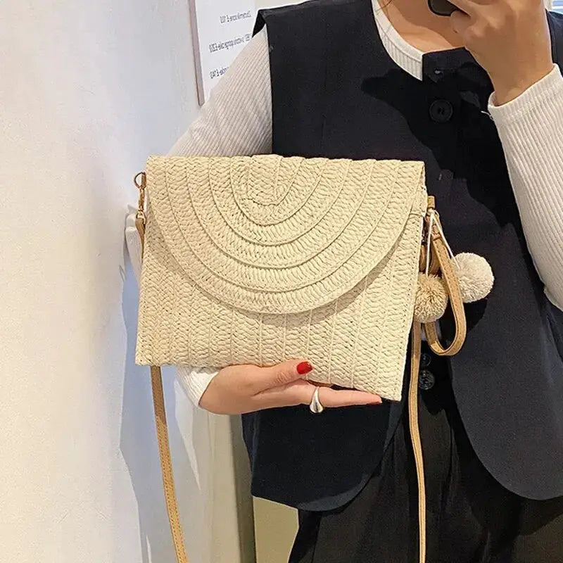 Handmade straw crossbody bag with envelope flap, beige woven texture and pom-pom charm
