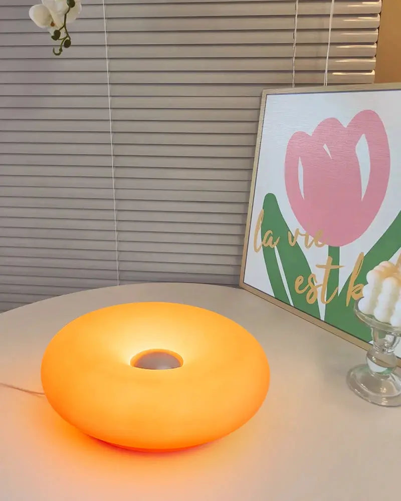 Bauhaus donut table lamp with USB plug emits an orange glow by Simples Market.