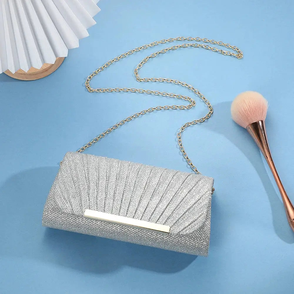 Silver sequined clutch bag with chain strap and metal bar accent for evening wear