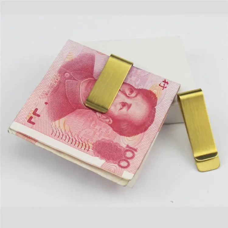 Two gold money clips resting on a stack of pink Chinese yuan banknotes