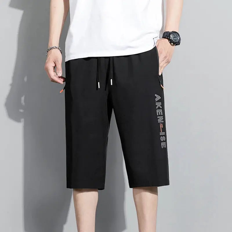 Men's black sports shorts with elastic drawstring waist, knee-length, side vertical text detail