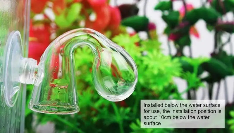 Aquarium CO2 drop checker in clear glass, attached to tank glass with suction cup, green plants backdrop.