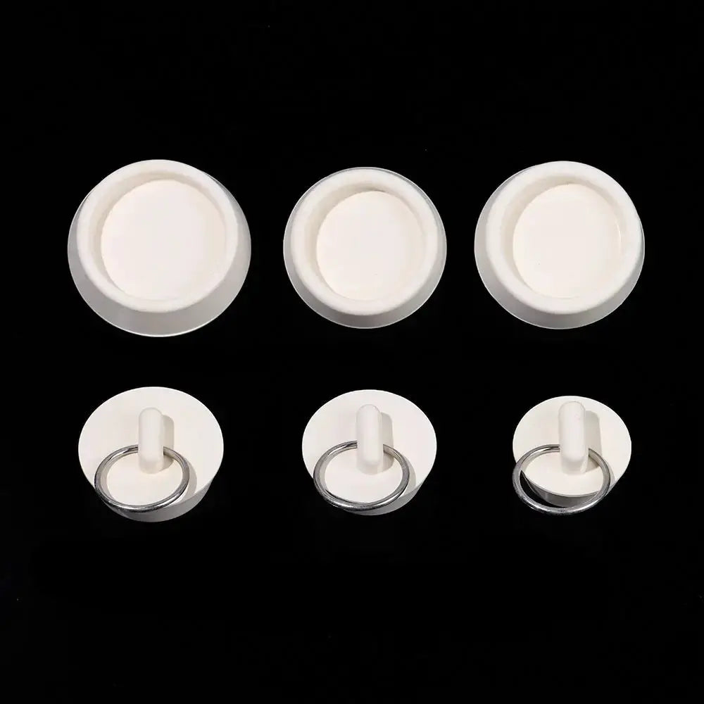Six white rubber bathroom plugs with metal ring handles; three flat caps and three with rings