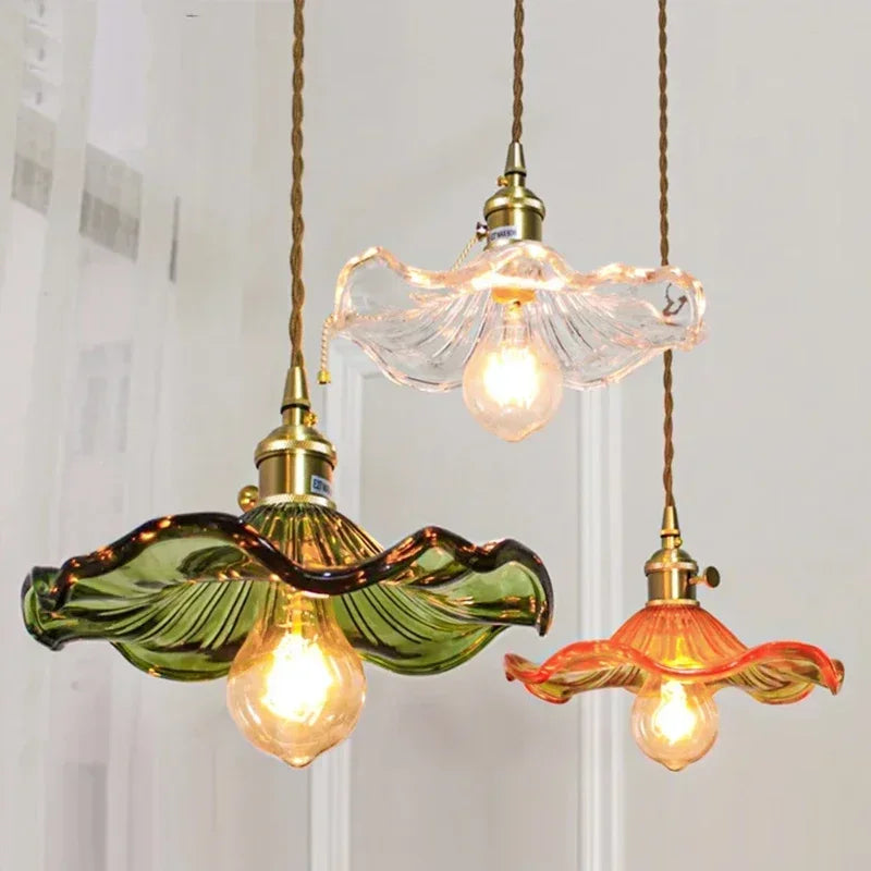 Three colorful glass pendant lights with brass fittings and twisted copper cords, green, clear, and orange shades