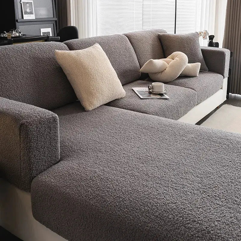 2026 Premium Winter Teddy Fleece Sofa Cover on a gray sectional with fluffy cream pillows, non-slip elastic.